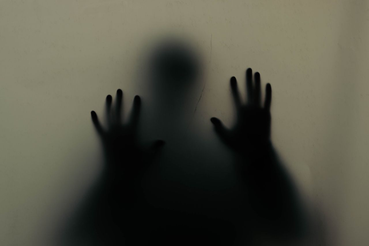 Services Mysterious silhouette of hands pressing against a translucent wall, creating an eerie atmosphere.