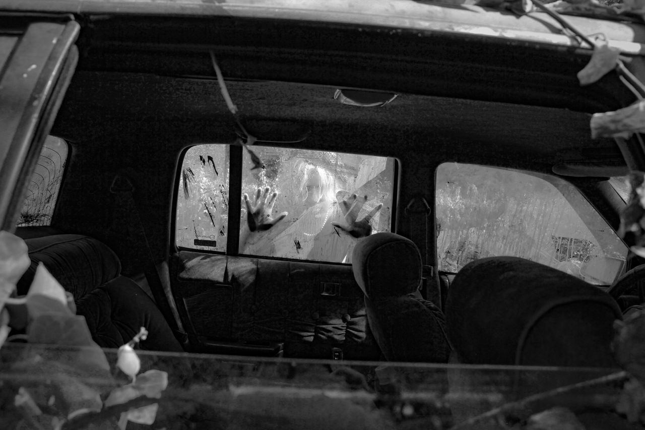 Mastering the First Impression: Your intriguing post title goes here Black and white photo of a ghostly figure outside an abandoned car, creating a haunting atmosphere.