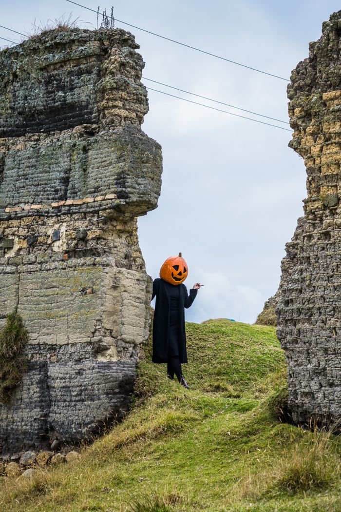 Services A person in a pumpkin head costume amidst historic ruins in Guasca, Colombia.